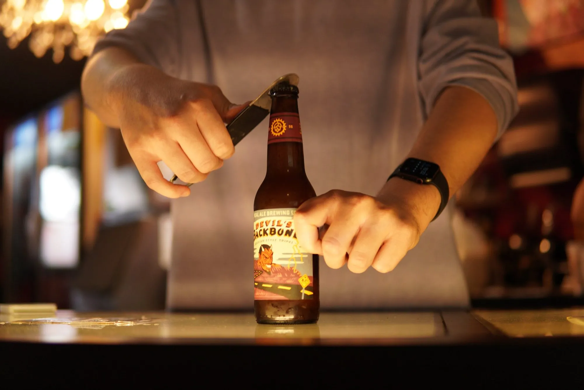 A bartender opening a bottle of Texas craft beer at the bar