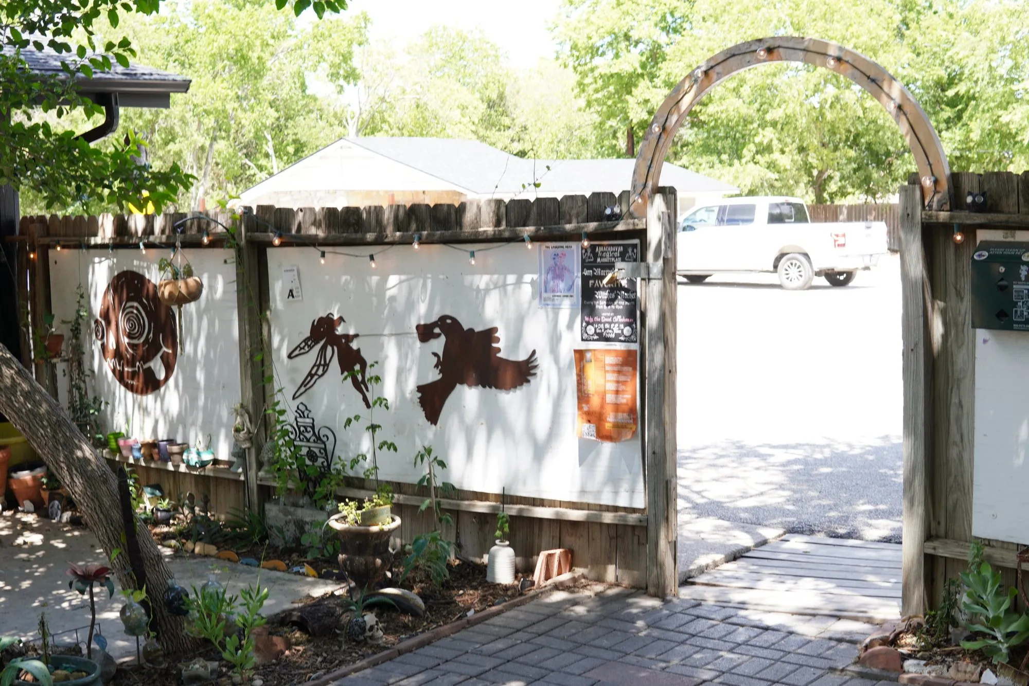 The courtyard gate with a metal arch and painted panels on the fence