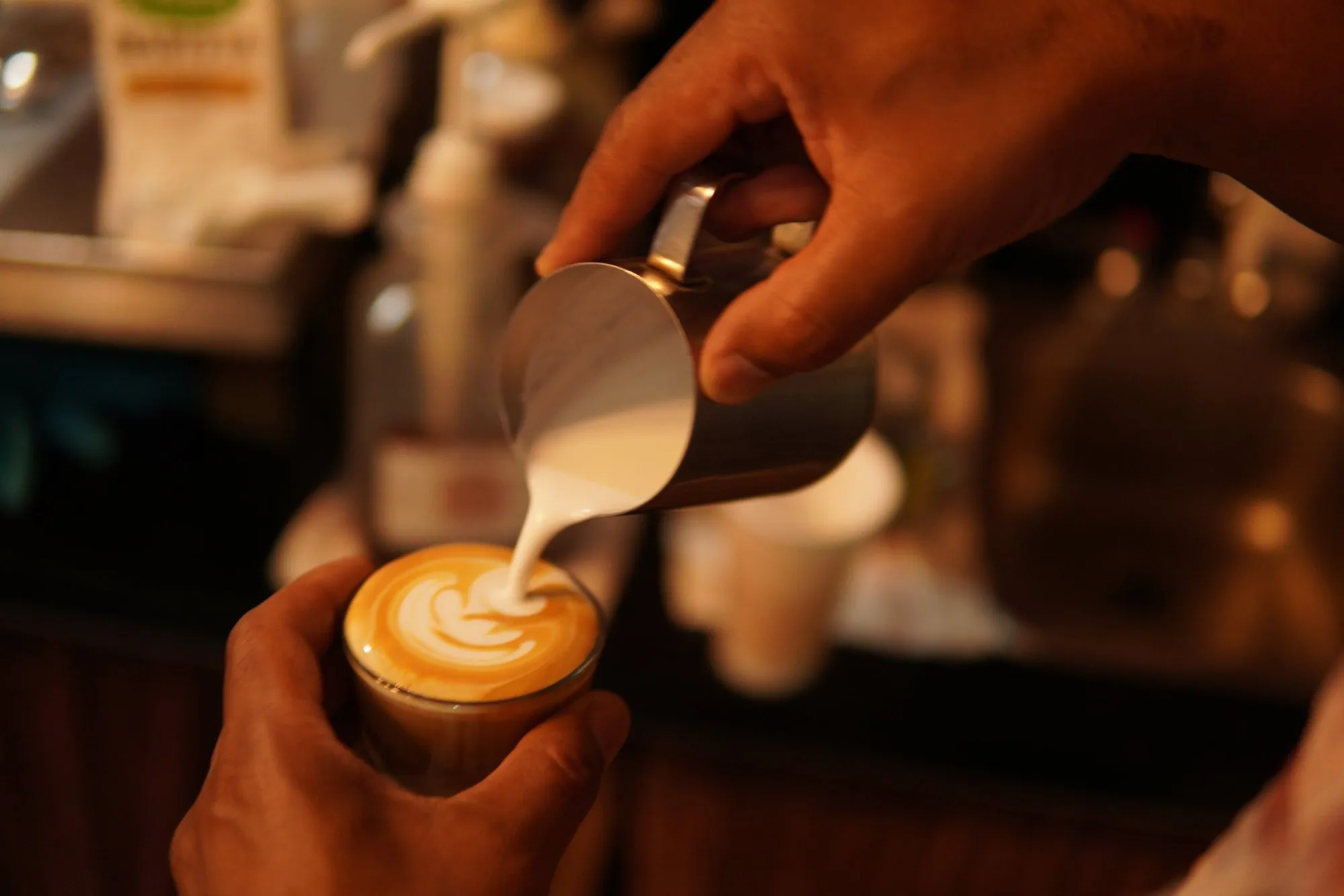 A barista pouring latte art into a cup