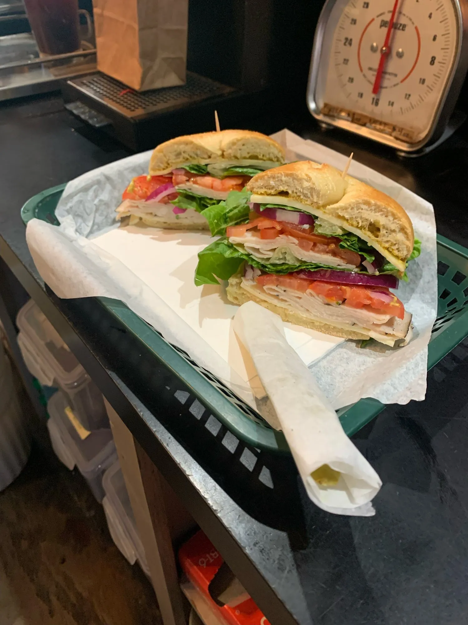 A turkey sandwich on a bagel with lettuce, tomato and red onion