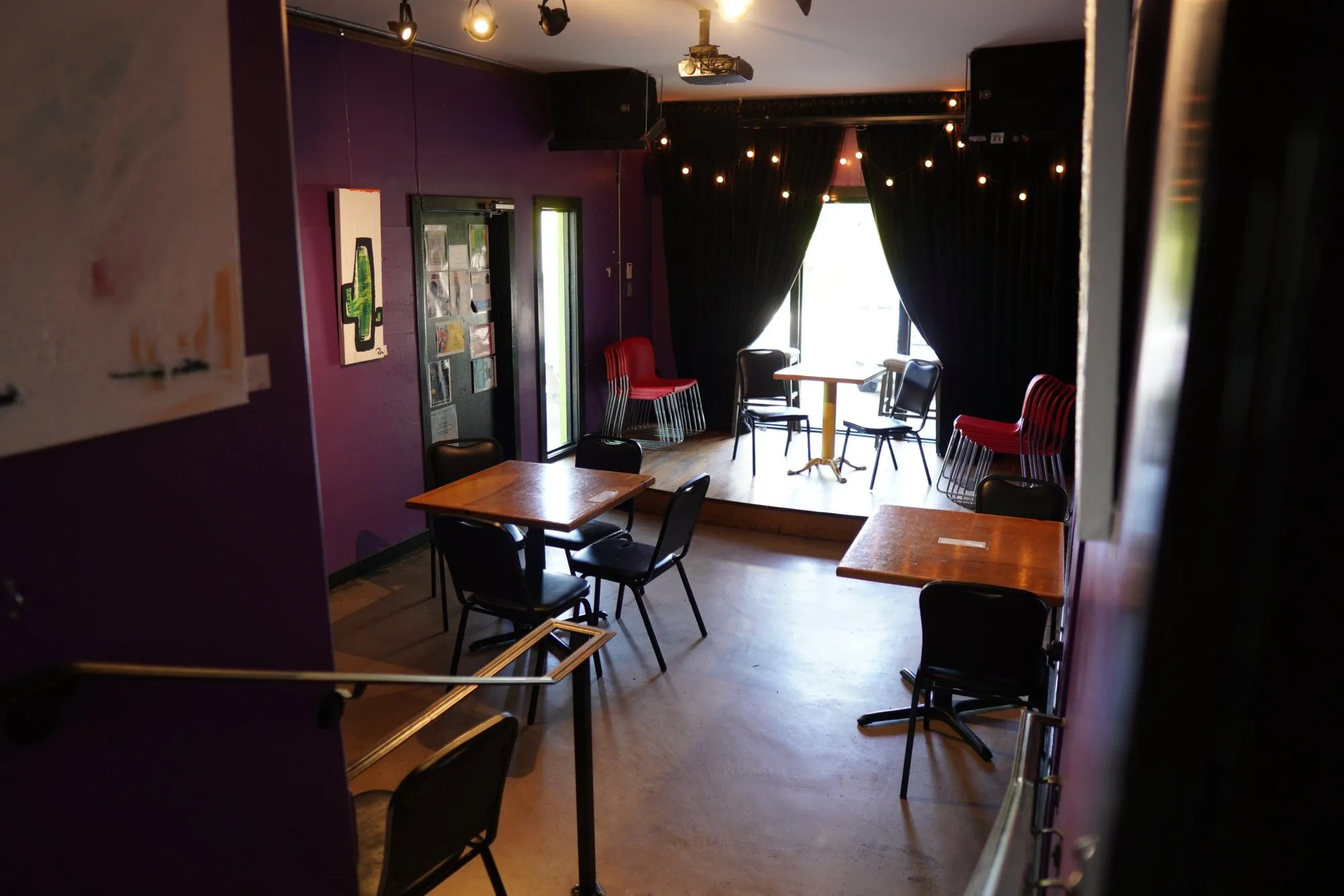 The stage room with purple walls, string lights and small tables